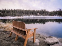 a wooden bench sits on the shore of a lake