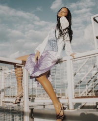 a woman in a purple dress posing on a railing
