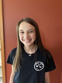 a young girl wearing a black shirt with a smiley face on it