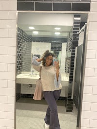 a woman taking a selfie in a bathroom mirror
