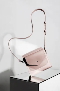 a pink cross body bag sitting on a table