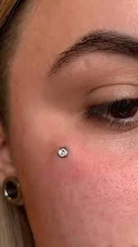 a close up of a woman's eye with a small piercing