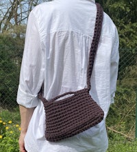 a woman wearing a white shirt holding a crocheted bag