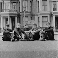 a group of young men sitting on the street in front of a building