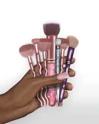 a hand holding a set of makeup brushes