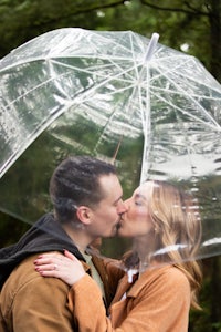 a couple kissing under a clear umbrella