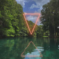 a neon triangle is reflected in a body of water