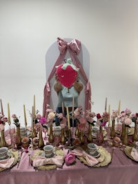 a table set up with pink flowers and candles