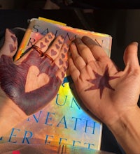 two hands holding a book with hearts painted on them