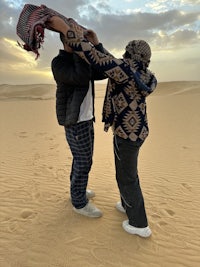 two people standing on the sand in the desert