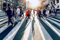 a group of people crossing a street at sunset
