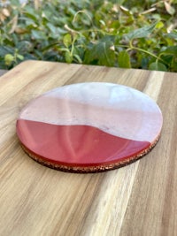 a pink and white coaster on a wooden table