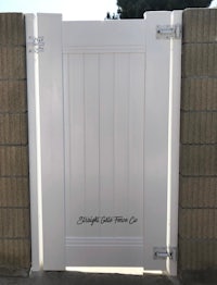 a white gate with a brick wall behind it