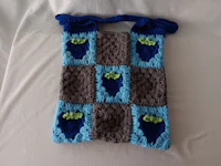 a blue and green crocheted bag with grapes on it