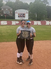 two softball players posing for a picture on a baseball field