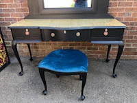 a black dressing table with a blue velvet stool
