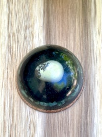 a blue and green egg on top of a wooden table