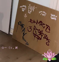 a piece of cardboard with graffiti on it next to a door