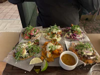 five tacos on a wooden tray