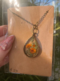 a person holding a necklace with a flower on it
