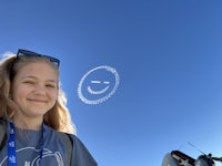 a girl is looking up at a helicopter in the sky