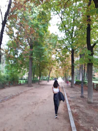 a woman walking down a dirt path in a park