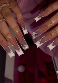 a woman's nails are decorated with rhinestones and rhinestones