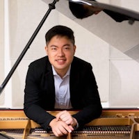 a man in a suit is leaning against a piano