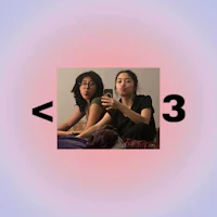 two women taking a picture of each other in front of a pink background