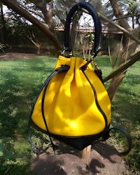 a yellow and black bucket bag hanging from a tree