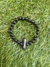 a black beaded bracelet sitting on grass