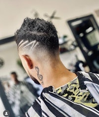 a man in a barber shop with a tattoo on his head