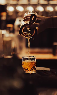 a person pouring a drink into a glass