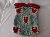 a crocheted strawberry bag on a bed