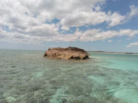 a rock in the middle of the ocean with clear water