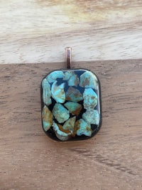 a square glass pendant with turquoise stones on it