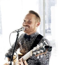 a man playing an acoustic guitar into a microphone
