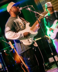 a man playing a guitar in front of a microphone