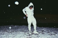 a man in a white hoodie standing in the snow