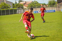 two young men kicking a soccer ball on a field