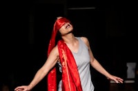 a woman in a red dress is holding a red scarf