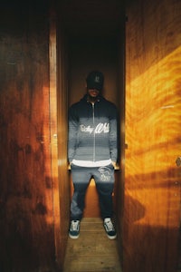 a man standing in a doorway wearing a hat and sneakers