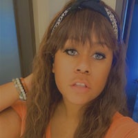 a woman in an orange shirt with a bandana on her head