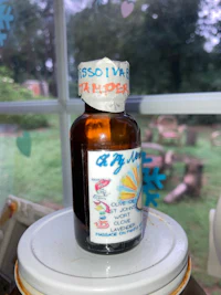 a bottle of essential oil sitting on a table in front of a window