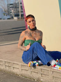 a woman with tattoos sitting on a concrete wall