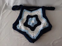 a blue and white crocheted bag on a bed