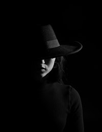 a woman wearing a black hat in the dark
