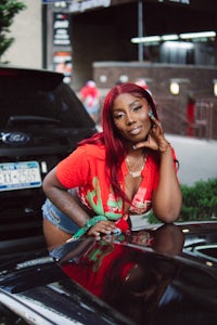 a woman leaning on the hood of a car