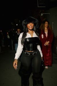 a woman in black pants and a fur hat walking down the street