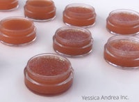 a group of small jars of lip balm sitting on a white surface